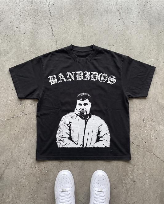 BANDIDOS CHAPO TEE laid flat on concrete – black tee with white BANDIDOS logo and portrait graphic