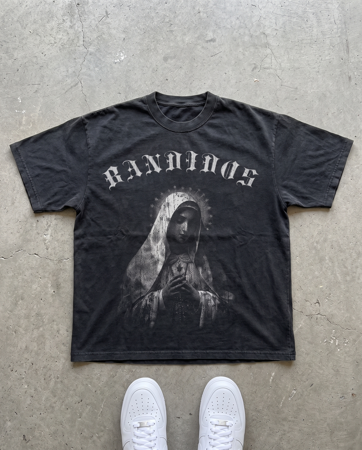 VIRGEN TEE laid flat on concrete – faded black tee with gray BANDIDOS logo and Virgin Mary graphic