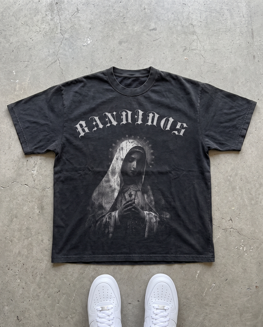 VIRGEN TEE laid flat on concrete – faded black tee with gray BANDIDOS logo and Virgin Mary graphic