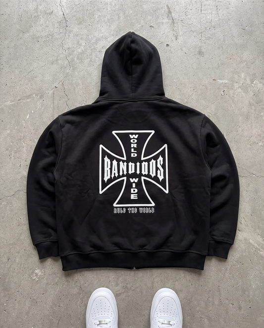 BANDIDOS STAPLE HOODIE back laid flat on concrete – black zip hoodie with white BANDIDOS cross graphic